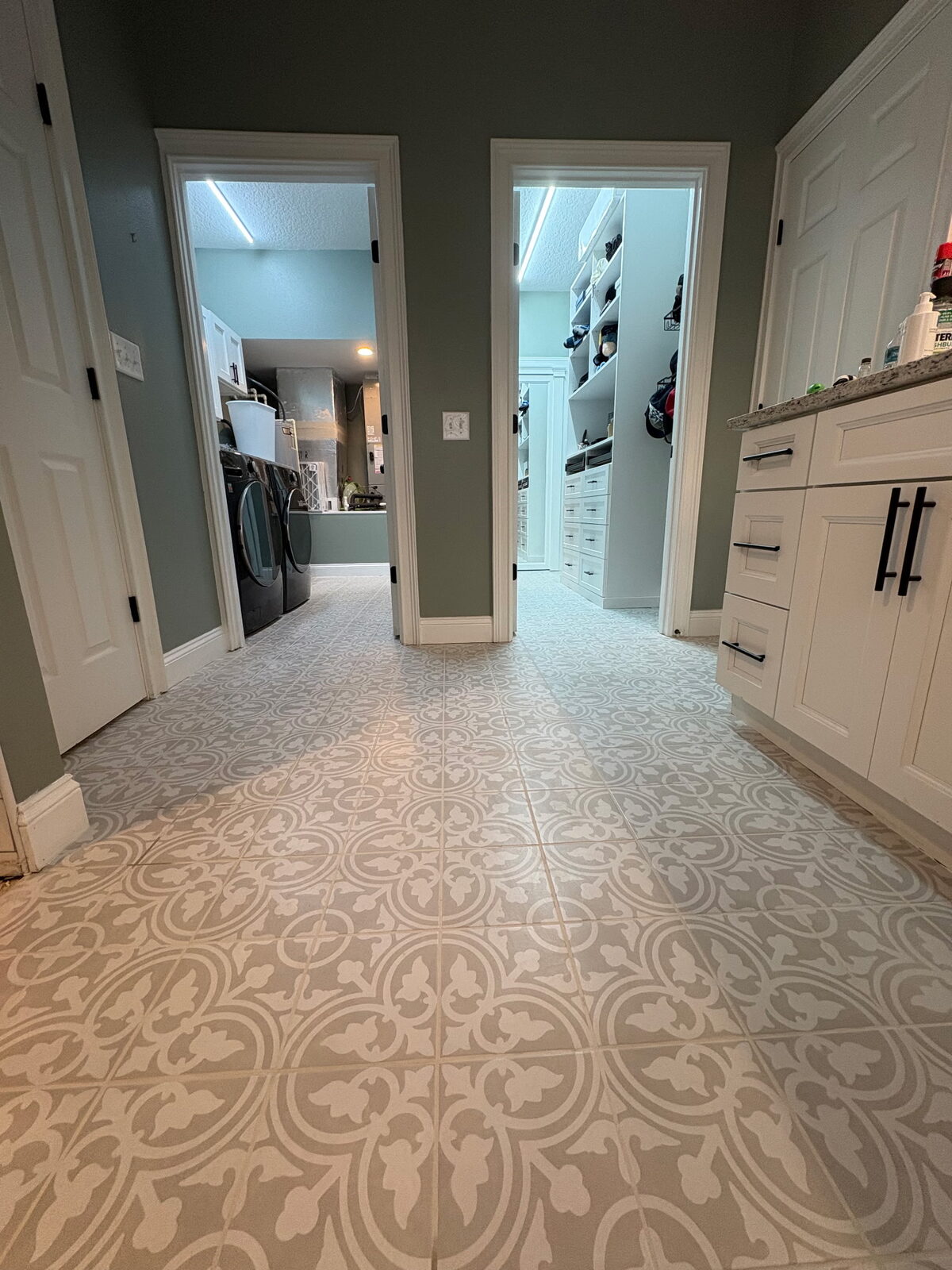 Patterned tile flooring installed through a remodeled laundry and storage area.