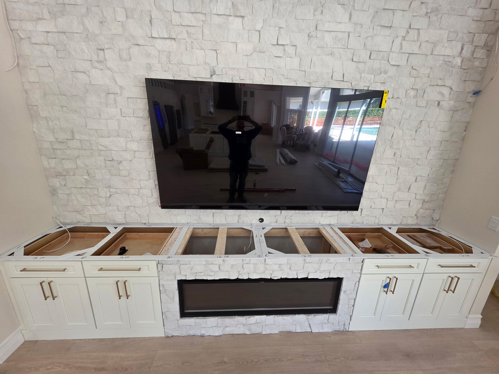 Interior remodeling project with a custom media wall, fireplace surround, and built-in cabinetry.