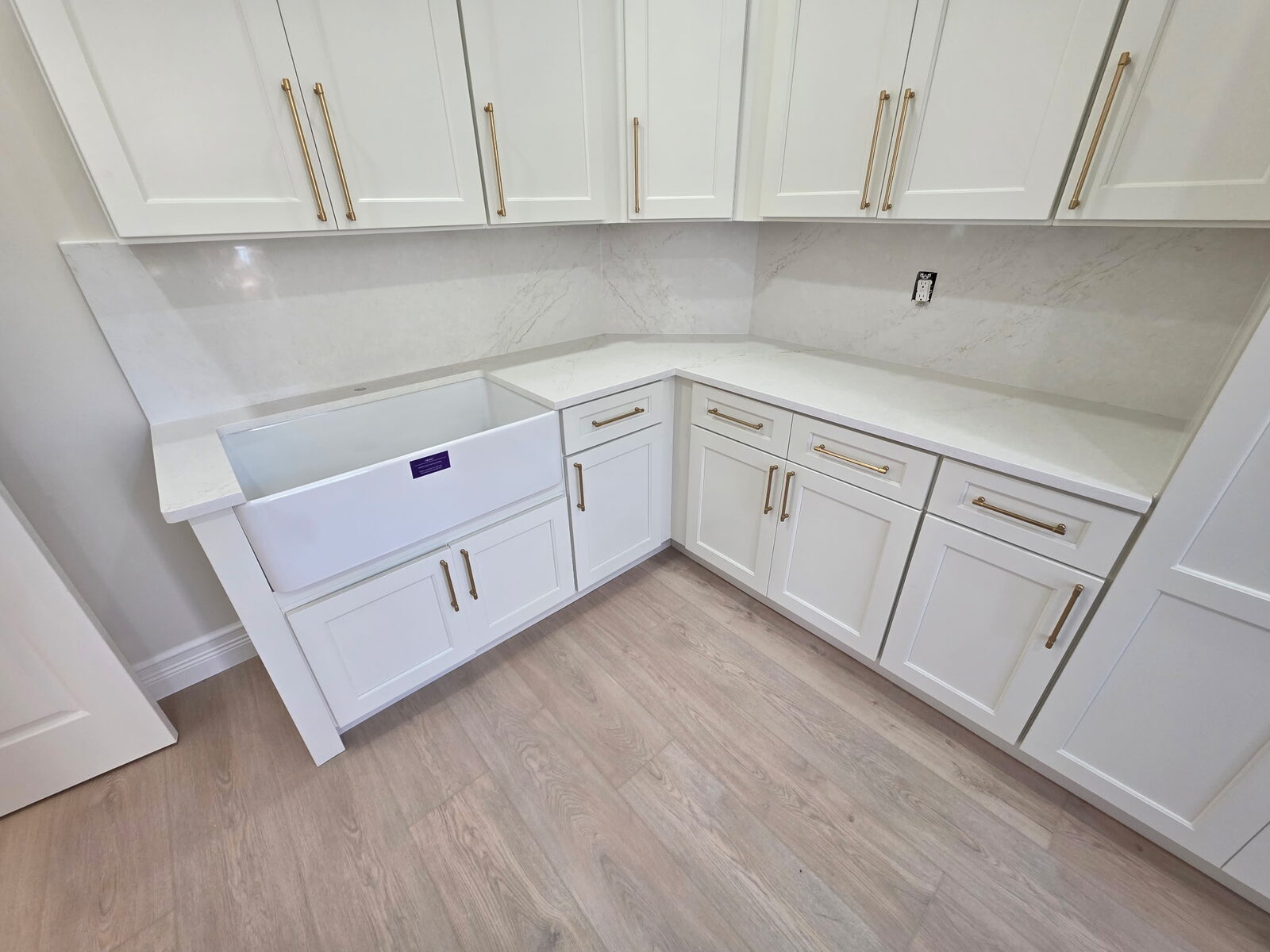 Custom white cabinet installation with brass hardware and integrated farmhouse sink.